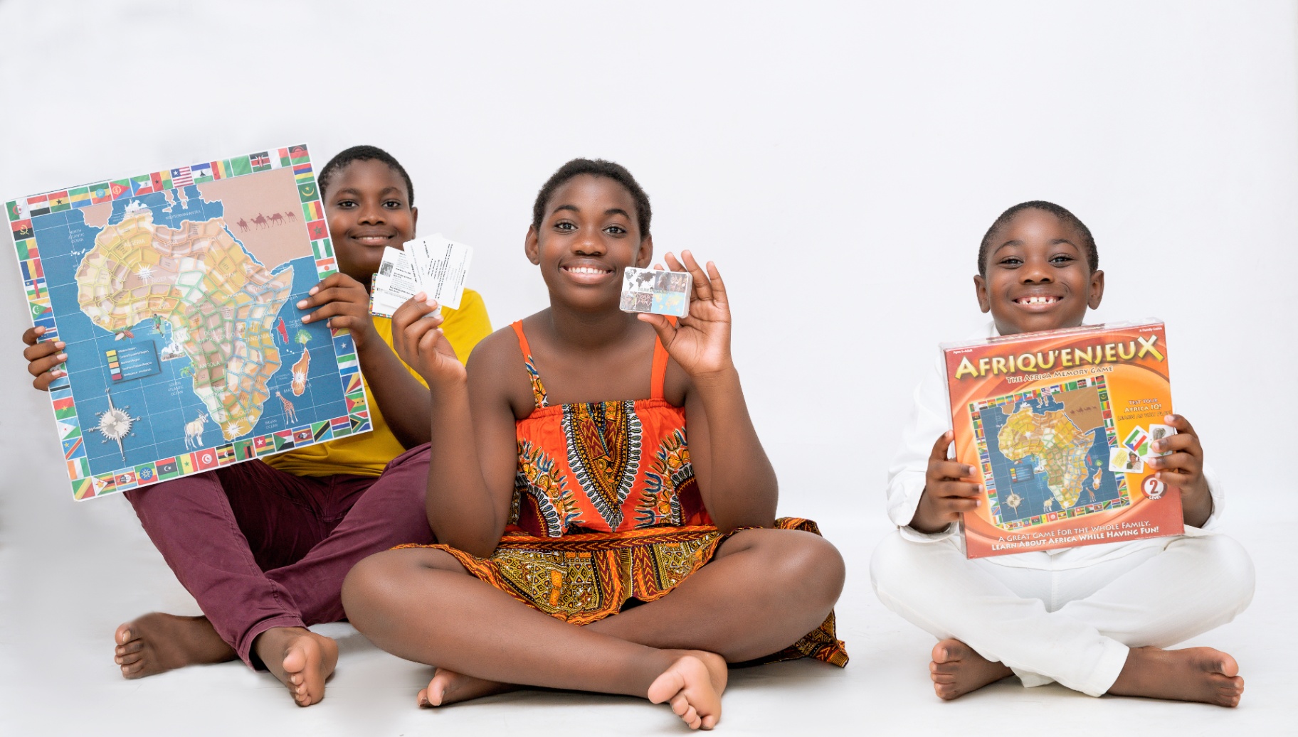 Three children showing the board, cards, and box